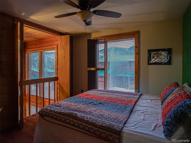 bedroom featuring carpet, ceiling fan, and wooden walls