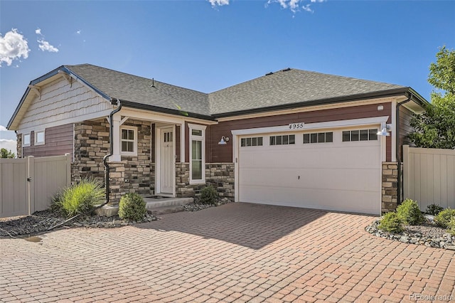 4955 N Picadilly Ct, Aurora, CO 80019 - view of front facade with stone siding, decorative driveway, an attached garage, and roof with shingles