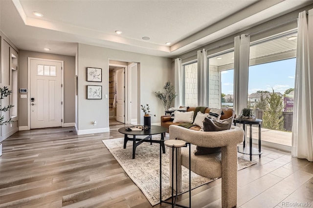 4955 N Picadilly Ct, Aurora, CO 80019 - living area featuring a tray ceiling, baseboards, recessed lighting, and light wood-style flooring