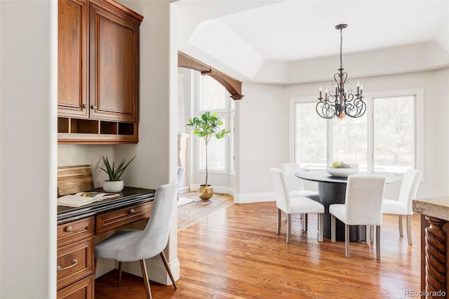 dining area featuring baseboards, a notable chandelier, light wood-style flooring, and built in study area