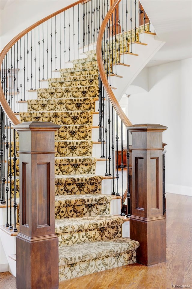 stairway with baseboards, a high ceiling, and wood finished floors