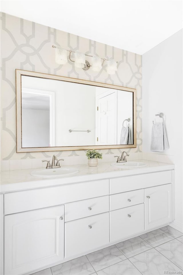 bathroom with a sink, wallpapered walls, double vanity, and marble finish floor