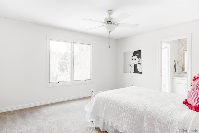 carpeted bedroom featuring baseboards, a ceiling fan, and ensuite bath