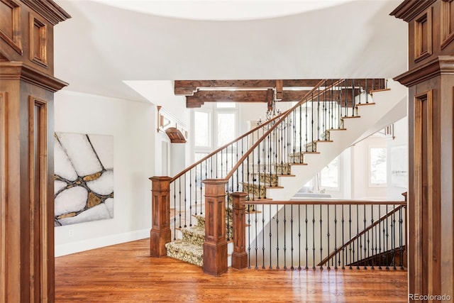 staircase featuring plenty of natural light, baseboards, and wood finished floors