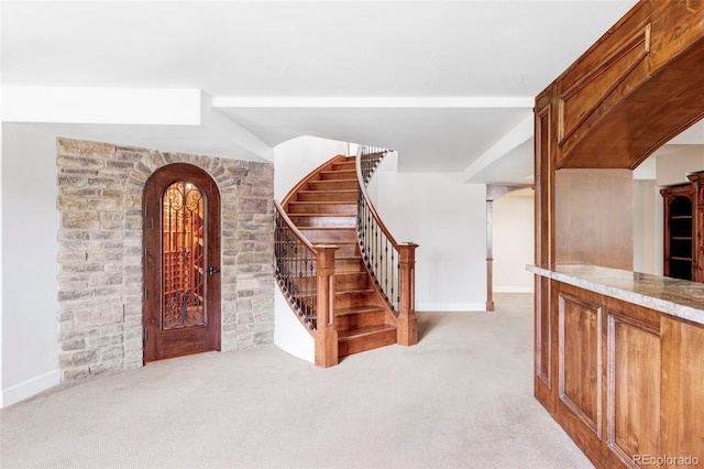 foyer entrance featuring stairway, arched walkways, and carpet flooring