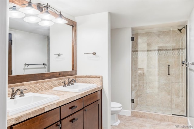 bathroom with double vanity, toilet, a shower stall, and a sink