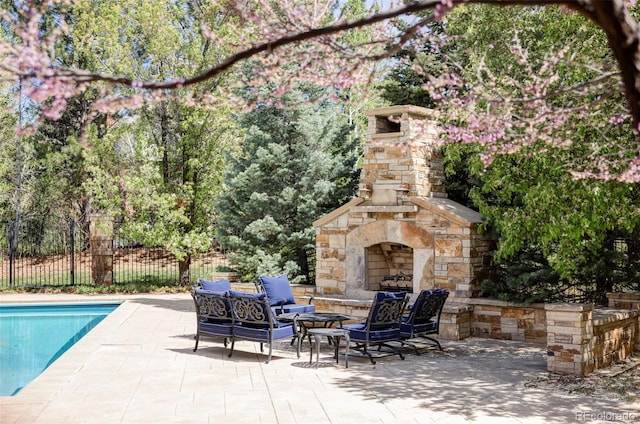 view of patio / terrace with a fenced in pool, an outdoor living space with a fireplace, and fence