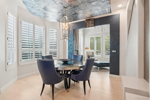 dining area with plenty of natural light, an inviting chandelier, and light hardwood / wood-style floors