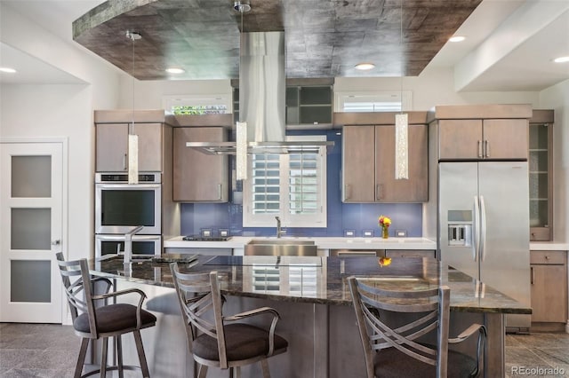 kitchen with appliances with stainless steel finishes, dark stone countertops, a breakfast bar area, and sink