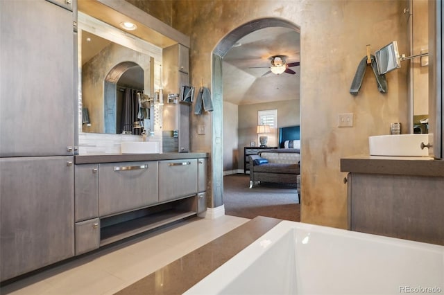 bathroom with tile patterned flooring, vanity, a washtub, ceiling fan, and vaulted ceiling