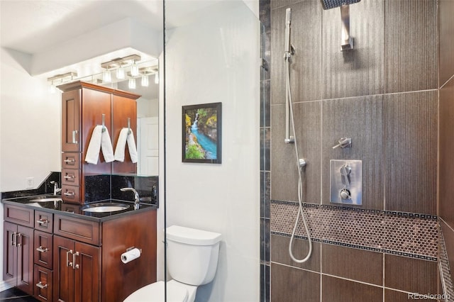 bathroom featuring toilet, a tile shower, and vanity