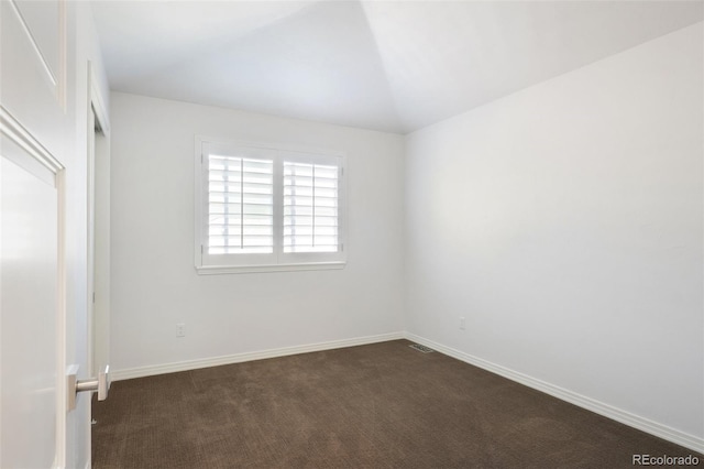 empty room with lofted ceiling and dark carpet