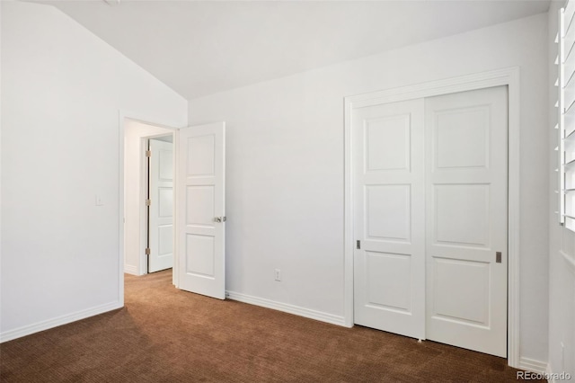 unfurnished bedroom featuring lofted ceiling, a closet, and carpet floors