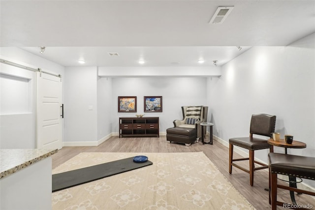 living area featuring a barn door and light hardwood / wood-style flooring