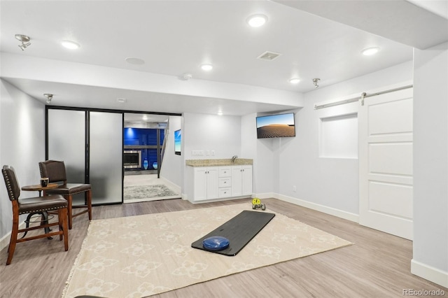 exercise room featuring a barn door and light wood-type flooring