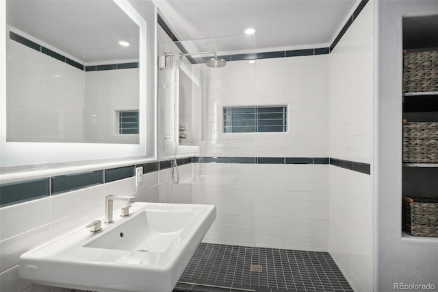 bathroom with tile walls, a tile shower, backsplash, and sink