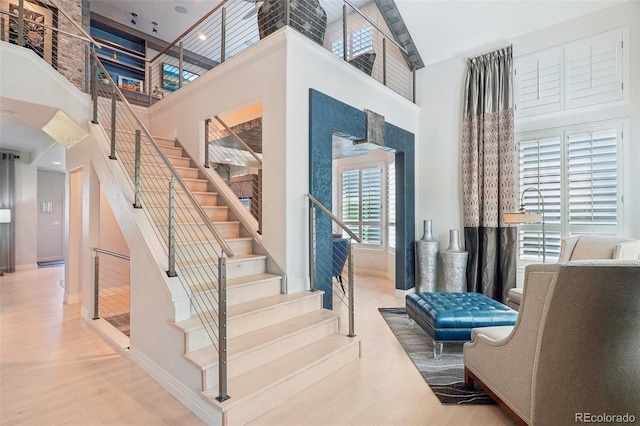 stairs featuring high vaulted ceiling and hardwood / wood-style flooring