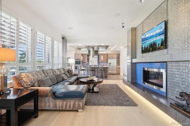 living room with a tiled fireplace and light hardwood / wood-style flooring