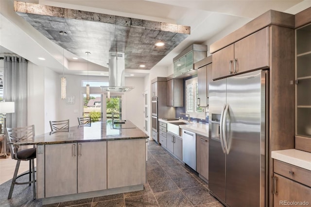 kitchen featuring a center island, stainless steel appliances, light brown cabinets, island exhaust hood, and a kitchen breakfast bar