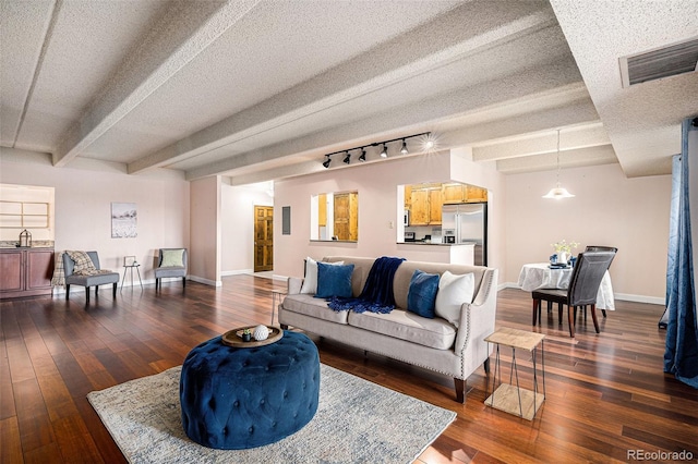 living room featuring dark wood-type flooring, baseboards, visible vents, and a textured ceiling