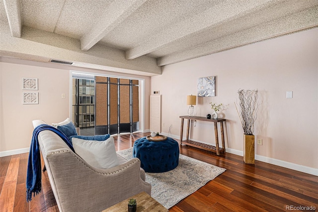 living room featuring visible vents, beam ceiling, a textured ceiling, wood finished floors, and baseboards