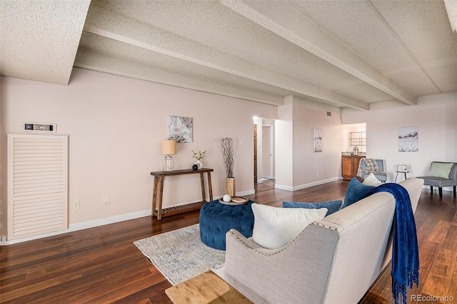 living room featuring beamed ceiling, a textured ceiling, baseboards, and wood finished floors