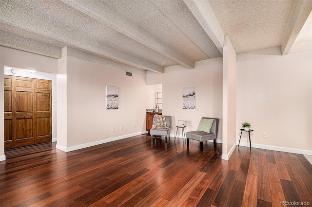 living area featuring visible vents, beam ceiling, a textured ceiling, hardwood / wood-style floors, and baseboards