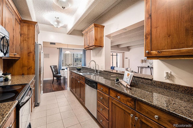 kitchen with dark stone counters, light tile patterned flooring, a sink, appliances with stainless steel finishes, and a textured ceiling