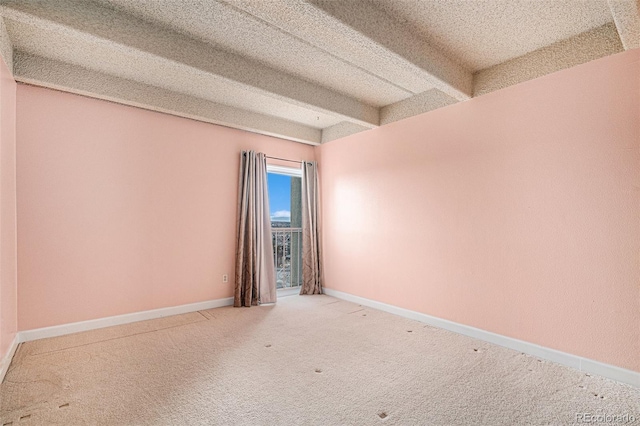 carpeted empty room featuring beam ceiling, baseboards, and a textured ceiling