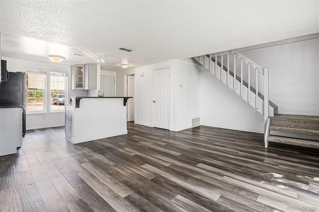 1534 S Ouray Cir Unit B, Aurora, CO 80017 - unfurnished living room with a textured ceiling, stairway, dark wood-style floors, and baseboards