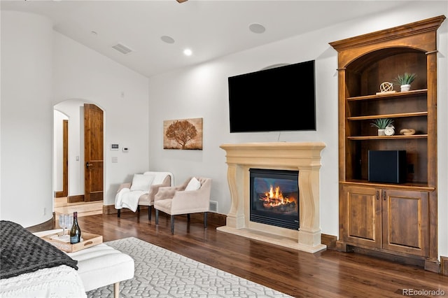 662 Yankakee Dr, Castle Rock, CO 80108 - living area featuring a glass covered fireplace, dark wood finished floors, lofted ceiling, visible vents, and arched walkways