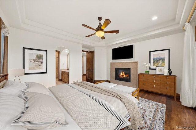 662 Yankakee Dr, Castle Rock, CO 80108 - bedroom with a tray ceiling, baseboards, arched walkways, a tile fireplace, and wood finished floors