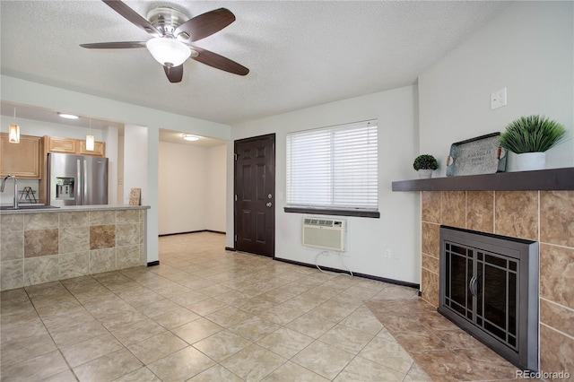 living area with light tile patterned flooring, a textured ceiling, a tile fireplace, a wall mounted air conditioner, and baseboards