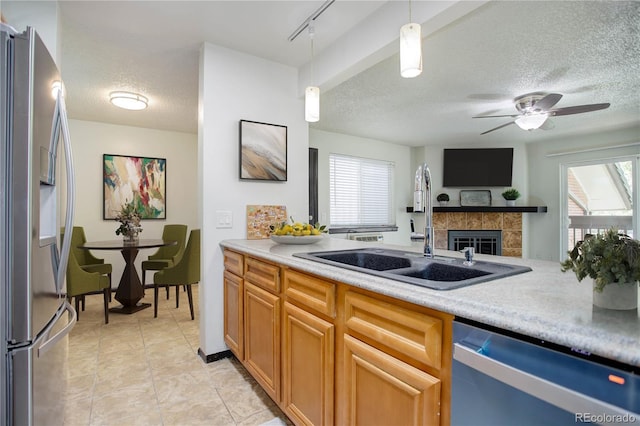 kitchen featuring appliances with stainless steel finishes, a sink, light countertops, pendant lighting, and a wealth of natural light