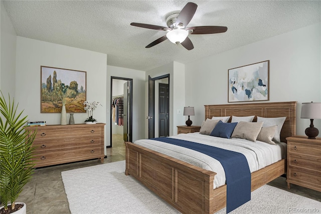 bedroom featuring a textured ceiling, a spacious closet, a closet, and a ceiling fan