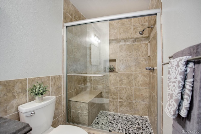 full bathroom with a stall shower, a textured wall, and toilet