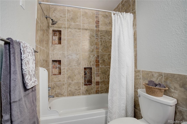 bathroom with toilet, shower / tub combo with curtain, and a textured wall