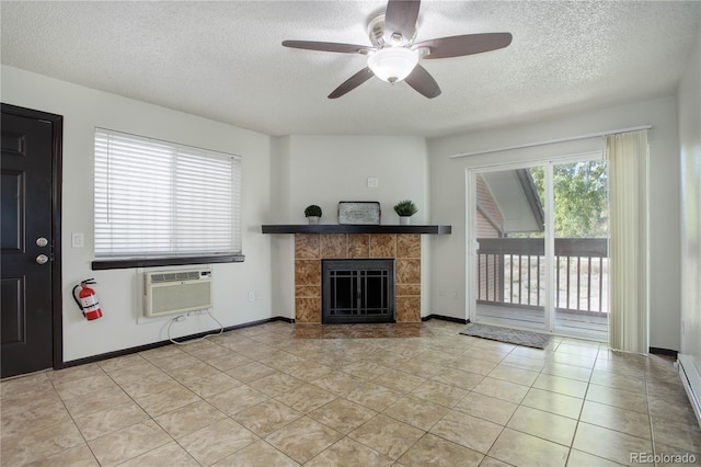 unfurnished living room featuring a wall unit AC, light tile patterned floors, a tiled fireplace, a textured ceiling, and baseboards