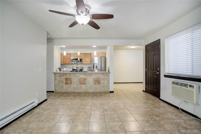 kitchen with a textured ceiling, light tile patterned floors, a baseboard heating unit, appliances with stainless steel finishes, and a wall mounted air conditioner