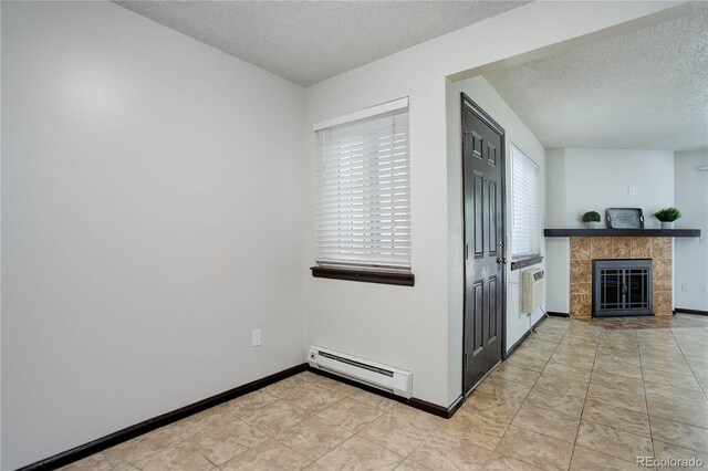 kitchen featuring light tile patterned floors, a baseboard heating unit, a textured ceiling, a tile fireplace, and baseboards