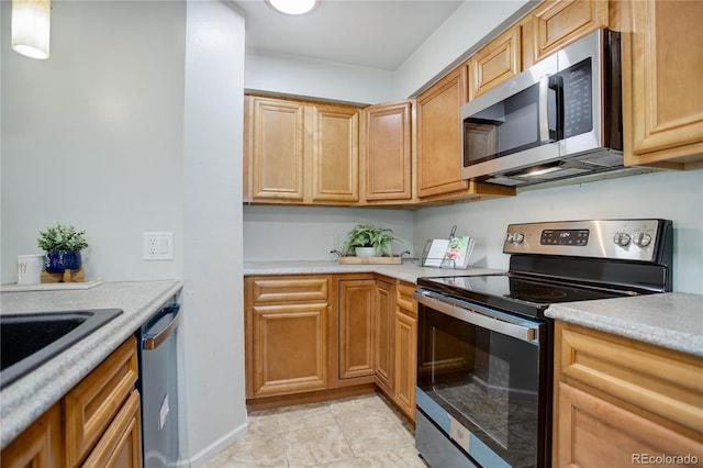 kitchen with brown cabinetry, stainless steel appliances, and light countertops