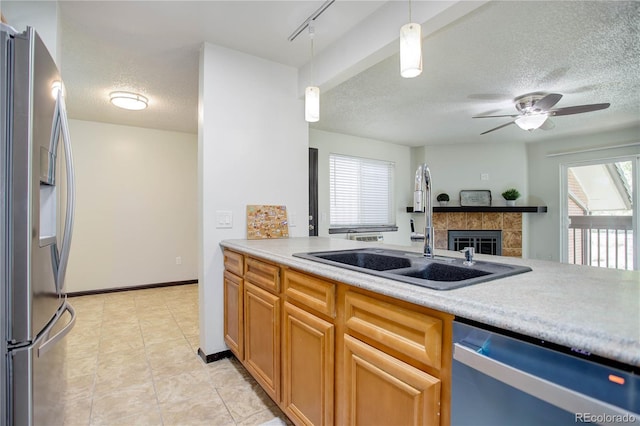 kitchen with decorative light fixtures, stainless steel appliances, light countertops, a sink, and plenty of natural light