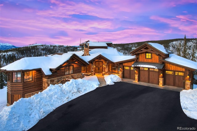 view of front facade featuring aphalt driveway, a mountain view, and stone siding