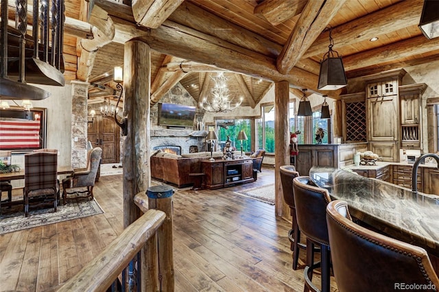 dining room with wood ceiling, an inviting chandelier, beamed ceiling, a fireplace, and hardwood / wood-style floors