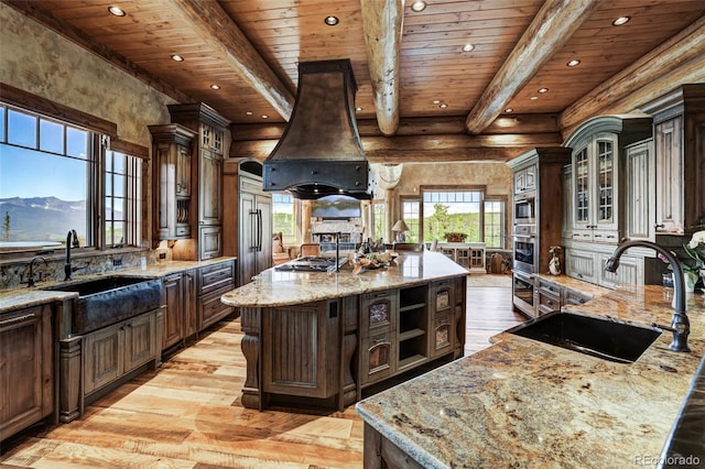 kitchen with sink, custom exhaust hood, a large island, dark brown cabinetry, and a mountain view