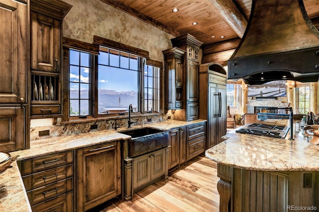 kitchen featuring custom exhaust hood, light stone countertops, sink, and wooden ceiling