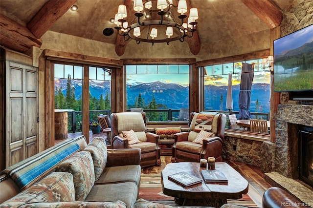 sunroom with lofted ceiling with beams, a chandelier, and a fireplace