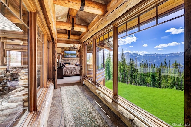 unfurnished sunroom featuring a stone fireplace, plenty of natural light, and a mountain view