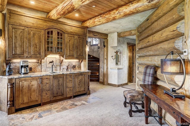 kitchen with sink, wood ceiling, light stone countertops, log walls, and beamed ceiling