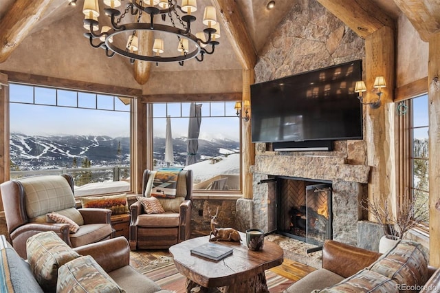 living area featuring plenty of natural light, a stone fireplace, wood finished floors, and an inviting chandelier